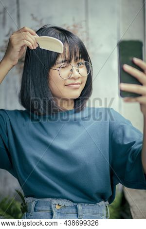 Asian Teenager Combing Forelock Hair By Comb And Smartphone Screen