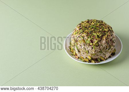 Sesame Halva With Chopped Pistachios On White Plate On Green Paper Background. Large Copy Space. Tra