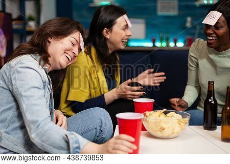 Laughing Multi-ethnic Friends Playing Who I Am Game Using Stickey Notes Enjoying Spending Time Toget