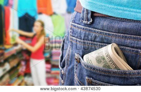 Nærbillede af penge i lommen mod pige på tøj butik