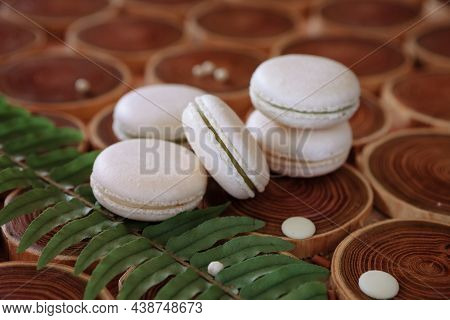 White Delicate Lowly Macaroons On A Wooden Background. The Pastel Tone Of The Cream Inside The Frenc