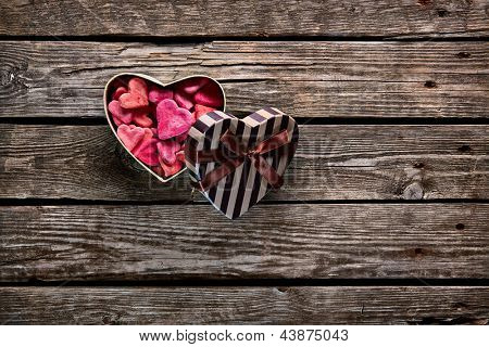 Cuore aperto a forma di scatola regalo di San Valentino con un mucchio di piccoli cuori all'interno su sfondo in legno vecchio.