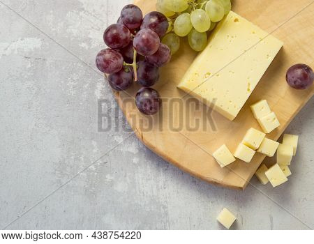 Light Meal With Sliced Cheese Next To A Bunch Of White And Red Grapes