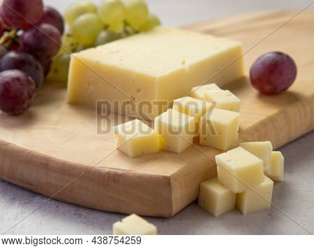 Light Meal With Sliced Cheese Next To A Bunch Of White And Red Grapes