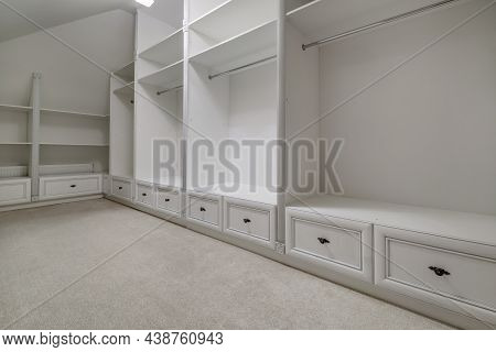 Rows Of Shelves And Clothes Hangers In Empty Big Wardrobe Room In Modern Apartment Or Hotel