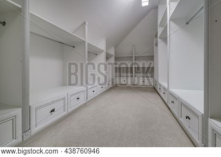 Rows Of Shelves And Clothes Hangers In Empty Big Wardrobe Room In Modern Apartment Or Hotel
