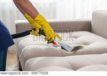 Close-up Of Housekeeper Holding Modern Washing Vacuum Cleaner And Cleaning Dirty Sofa With Stain Wit