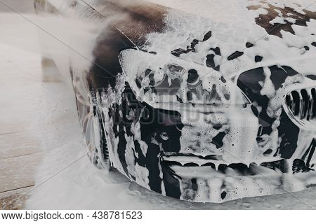 Close Up Of Black Car Surface In White Snow Foam During Carwashing And Cleaning Outdoors At Self-ser