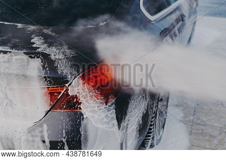 Carwash Equipment. Vehicle Covered In White Soapy Foam During Regular Wash Outdoors With Cleaning Pr