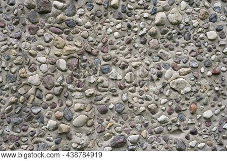 Different Shape Pebble Stones Stacked Into A Concrete Wall As Background