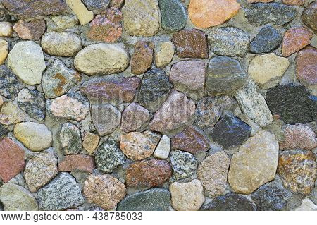 Close Up Of Shining Different Shape Pebbles Stacked Into A Cement Wall