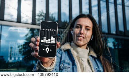 Audio Tour Online App On Digital Mobile Smartphone. Happy Young Student Woman Holding Phone Listenin