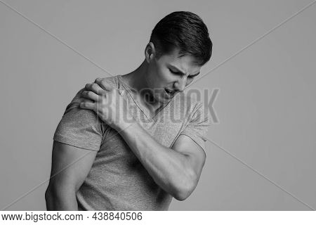 Sad Young Caucasian Handsome Male Presses His Hand To Sore Spot And Suffers From Shoulder Pain