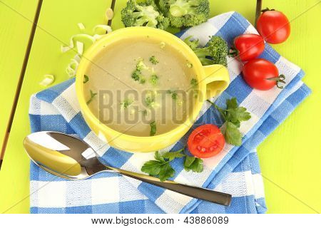 Dietní polévka se zeleninou v poháru na zelený dřevěný stůl detail