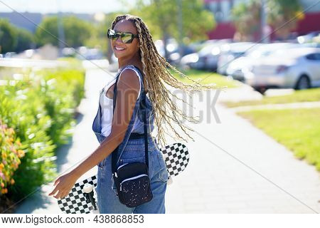 Young Black Woman Moving Her Coloured Braids In The Wind. Typical African Hairstyle.