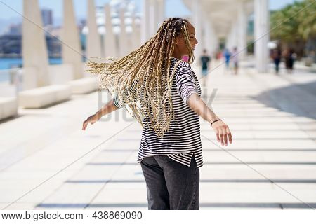 Young Black Female Moving Her Coloured Braids In The Wind. Typical African Hairstyle.