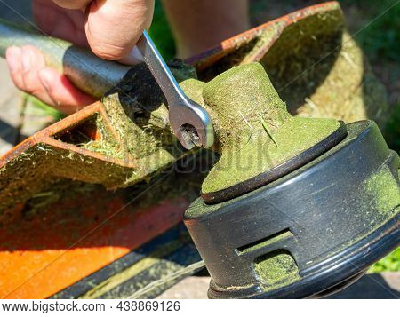 Close-up Of A Grass Mowing Trimmer, The Screw On The Gearbox Is Unscrewed With A Wrench. Maintenance