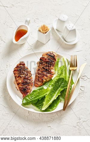 Seared Chicken Breasts With Fresh Romaine Lettuce Leaves On A White Plate With Golden Cutlery On A W