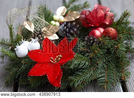 Christmas Wreath Decorated With Red Balls, Lights And Pinecones On Wood Background