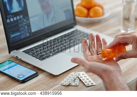 Hands Of Senior Man Using Telemedicine Website On Laptop To Talk To Doctor And Taking Prescribed Pil