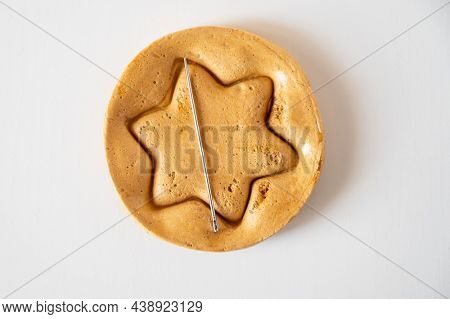 Brown sugar caramel candy cookies with a metal needle in the shape of a star on a white background.