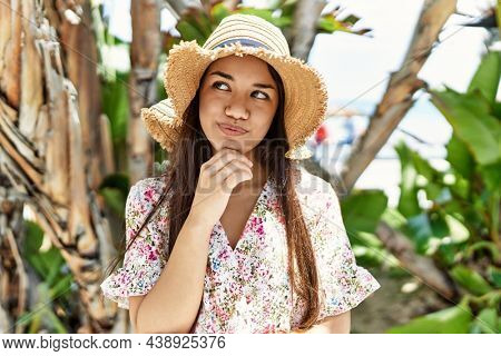 Young brunette woman outdoors on a sunny day of summer smiling happy and positive, thumb up doing excellent and approval sign 