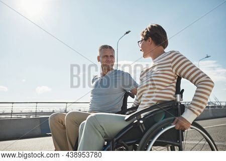 Side View Portrait Of Adult Couple In Wheelchairs Chatting Outdoors And Enjoying City Life, Copy Spa