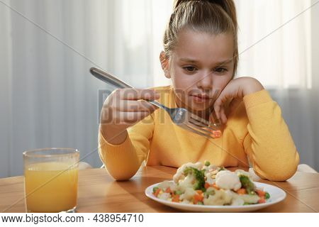 Cute Little Girl Refusing To Eat Vegetable Salad At Home