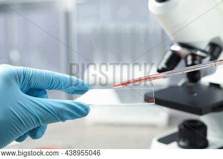 Scientist Dripping Sample Of Red Liquid Onto Microscope Slide In Laboratory, Closeup
