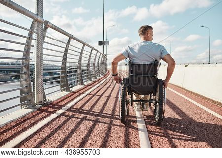 Back View Portrait Of Man In Wheelchair In Accessible City Environment Outdoors Lit By Sunlight, Cop