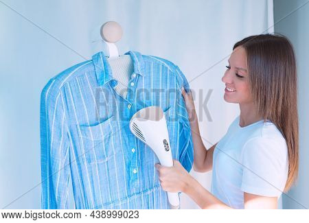Woman Ironing Blue Dress With Garment Steamer. Woman With Steamer Cleaning Clothes At Home