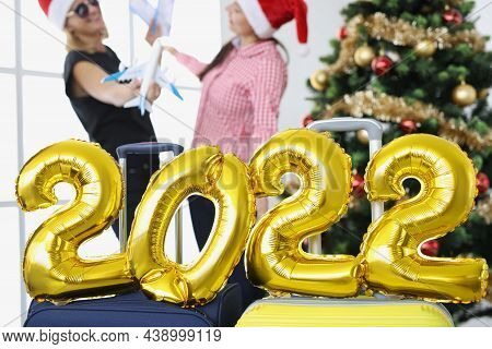 Numbers 2022 On Suitcases In Of Christmas Tree And Women Holding Airplanes And Tickets. Traveling Fo