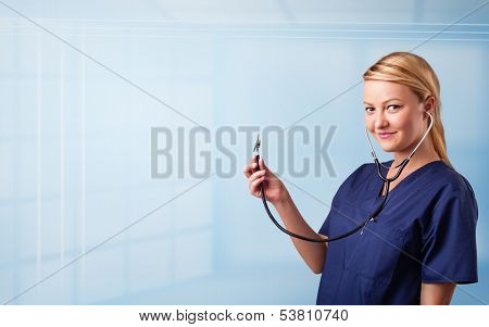 Pretty young nurse in hospital listening to empty copy space with sthetoscope