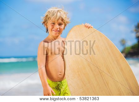 Happy Young boy having fun at the beach on vacation, with skimboard
