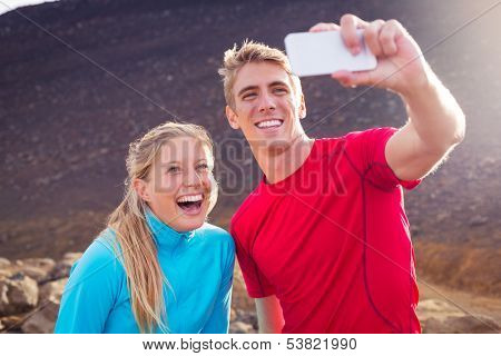Young attractive athletic couple taking photo of themselves with smart phone, making a selfie