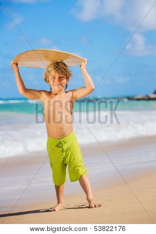 Happy Young boy having fun at the beach on vacation, with skimboard