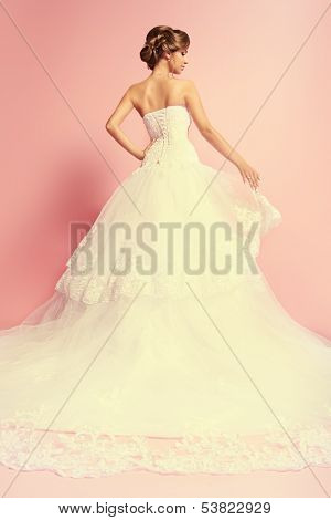 美丽迷人的新娘在豪华礼服站在一起她回来。