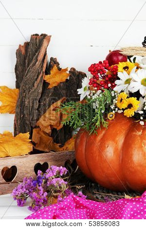 Beautiful autumn composition in pumpkin with decorative box on table on wooden background