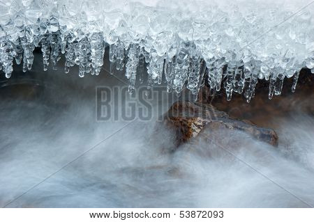 Icicle frozen on a branch of a tree near a mountain stream. The winter nature 