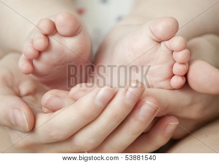 newborn baby feet on female hands 