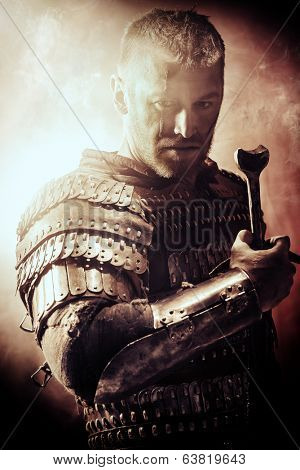 Portrait of a courageous ancient warrior in armor with sword.