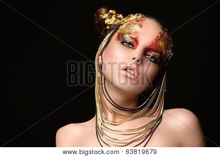 Art project: beautiful woman with golden make-up. Jewelry, make-up. Fashion. Over black background.