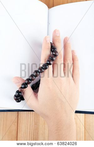 Hands with rosary and holy book, on light background