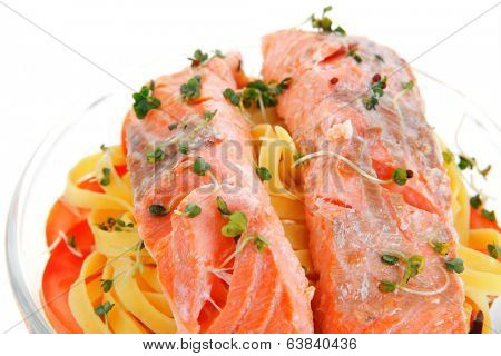 fresh fried natural pink salmon on italian traditional tagliatelle backed with tomato and vegetables isolated over white background