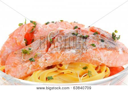 fresh fried natural pink salmon on italian traditional tagliatelle backed with tomato and vegetables isolated over white background