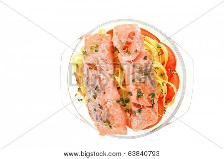 fresh fried natural pink salmon on italian traditional tagliatelle backed with tomato and vegetables isolated over white background