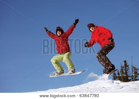 Two snowboarder jumping on the background of blue sky