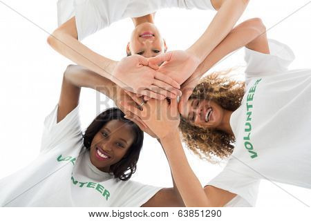 Happy volunteers putting hands together and looking down at camera on white background