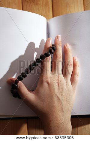 Hands with rosary and holy book, on light background