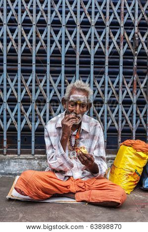 TIRUCHIRAPALLI, INDIA - FEBRUARY 14, 2013: Unidentified old Indian man eating in the street